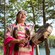 Una mujer con el atuendo tradicional de una comunidad indígena canta y toca el tambor junto a un lago